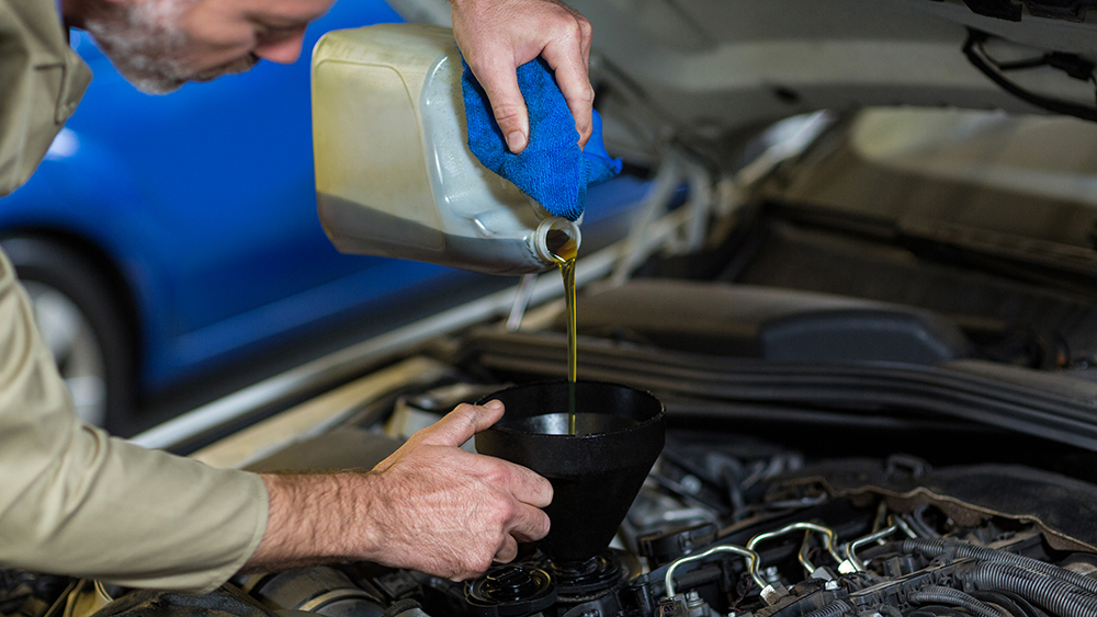 mechanic pouring synthetic oil into car engine